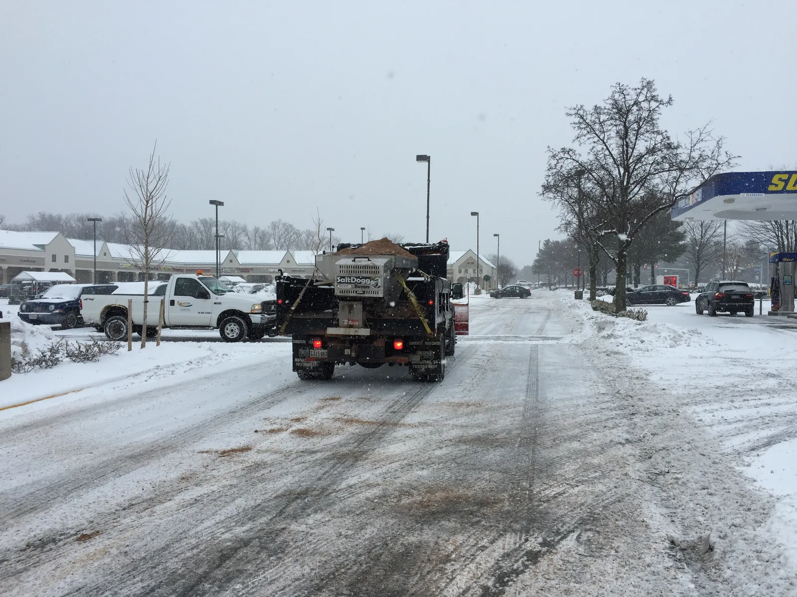 A salt spreader treating a commercial parking lot during snow