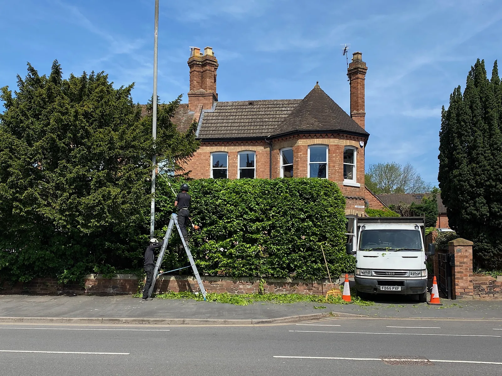 Crew trimming hedges and shrubs at a residential property